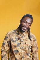 Cheerful positive man laughting at camera, having fun while posing over yellow background. Confident african american person with excited facial expression, enjoying free time during studio shot photo