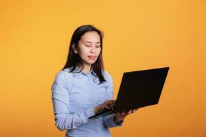 Filipino woman using laptop computer browsing webpages on internet, searching information for research project. Young adult using portable electronic pc to navigate on social media. Remote work photo