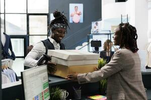 African american shopper holding packages fiiled with fashionable clothes, paying for merchandise at cash register in showroom. Customer buying stylish fashion collection, commercial activity photo