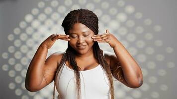 Confident woman applying face cream on bare skin to create beauty ad, using sunscreen or serum to protect luminous skin with imperfections. Young model posing with self confidence. photo