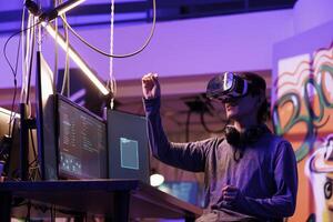 Hacker doing illegal activity in vr headset and exploring metaverse while breaking law. Criminal hacking server in virtual reality simulation while making gestures with hands photo