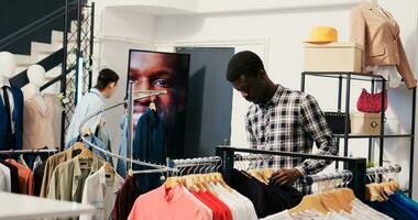 African american customer checking shirt fabric in modern boutique, wanting trendy clothes for new wardrobe. Shopaholic man shopping for fashionable merchandise in clothing store. Fashion concept photo