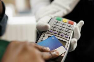 Close up of hotel guest paying for room at front desk, male hand holding plastic credit card making contactless payment. Cashless transactions and nfc technology in hospitality industry photo