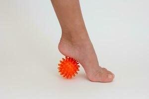 Cropped child leg doing exercises with spiky needle ball photo