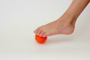 Cropped child leg doing exercises with spiky needle ball photo