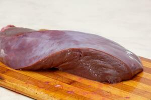 Raw beef liver on cutting board photo
