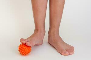 Cropped child legs doing exercises with spiky needle ball photo