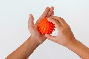 Cropped child hands doing exercise using spiky ball photo