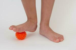 Cropped child legs doing exercises with spiky needle ball photo