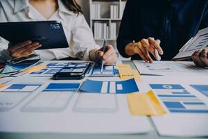 Close up ux developer and ui designer brainstorming about mobile app interface wireframe design on table with customer breif and color code at modern office.Creative digital development agency photo