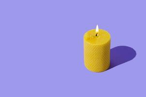 Creative layout of beeswax candle made with natural wax produced by honey bees on pastel violet background. Minimal concept. Trendy beeswax candle composition. Copy space. photo