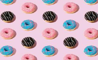 Creative pattern of colorful donuts on pastel pink background. Minimal concept. Trendy donuts pattern. Yummy food composition. Donuts aesthetic background. photo