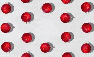 Creative trendy pattern made with red Christmas baubles on snowy background with copy space. Minimal Christmas or New Year concept. Winter holidays idea. Flat lay composition. Top of view. photo