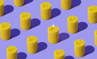 Creative pattern composition of beeswax candles made with natural wax produced by honey bees on pastel violet background. Minimal pattern background hope concept. Trendy beeswax candle idea. photo