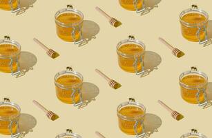 Creative pattern made with jar full of natural honey and honeycombs, honey bee and honey dipper on light beige background. Minimal nature concept. Trendy healthy food idea. Honey aesthetic background. photo