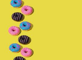 Creative arrangement of colorful donuts on light yellow background with copy space. Minimal food concept. Trendy yummy donuts idea. Donuts aesthetic background. photo