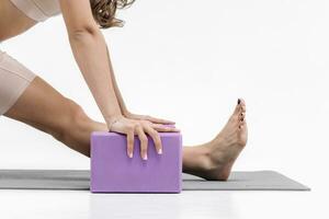 Close-up woman doing stretching exercises on a white background. Foam block Fitness Equipment photo