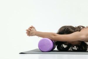 joven mujer haciendo extensión ejercicios en un blanco antecedentes. espuma rodillo masaje pelota, aptitud equipo para desencadenar puntos yo foto