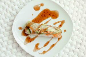 Spring rolls and spicy sauce on white background. Summer rolls with fresh vegetables and shrimps and peanut sauce. Vietnamese appetizer. Salad spring rolls with prawns. Healthy food concept. photo