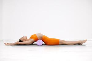 joven mujer haciendo extensión ejercicios en un blanco antecedentes. espuma rodillo masaje pelota, aptitud equipo para desencadenar puntos yo foto