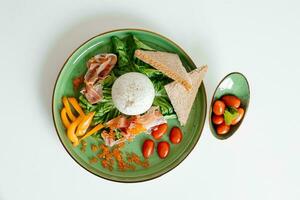 Healthy summer salad with burrata, jamon and tomatoes on green plate. Healthy eating. Portion of fresh gourmet burrata on white background photo