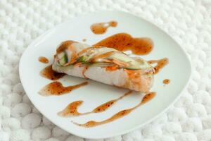 Spring rolls and spicy sauce on white background. Summer rolls with fresh vegetables and shrimps and peanut sauce. Vietnamese appetizer. Salad spring rolls with prawns. Healthy food concept. photo