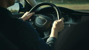 An unrecognizable man is driving his car. The shot shows hands on the steering wheel, the dashboard and the street. video