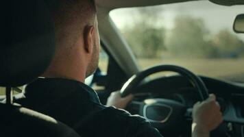 An unrecognizable man is driving his car. The shot shows hands on the steering wheel, the dashboard and the street. video