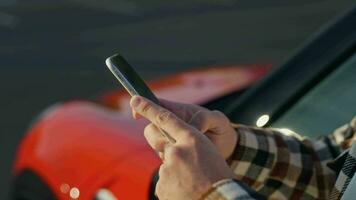 fermer. Masculin mains avec une téléphone intelligent sur le Contexte de une auto. en utilisant moderne applications à relier votre voiture et téléphone video