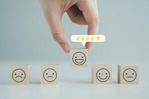 Hand choosing happy smiling face with 5 star on speech bubble. Feedback rating and positive service review. Customer experience, World mental health day, think positive, Emotion, satisfaction survey. photo