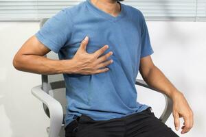 un hombre es experimentando cofre opresión debido a corazón enfermedad. foto