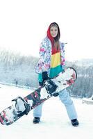 joven mujer participación tabla de snowboard en su espalda foto