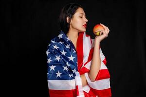 Portrait female athlete wrapped in American Flag against black background photo