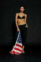 Portrait female athlete wrapped in American Flag against black background photo