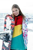 joven mujer participación tabla de snowboard en su espalda foto