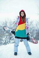 joven mujer participación tabla de snowboard en su espalda foto