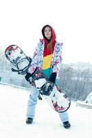 Young woman holding snowboard on her shoulders photo