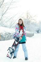 Young woman holding snowboard on her shoulders photo