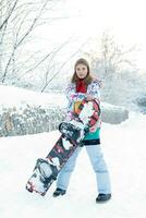 joven mujer participación tabla de snowboard en su espalda foto