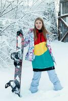 Young woman holding snowboard on her shoulders photo