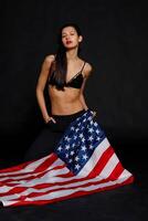 Portrait female athlete wrapped in American Flag against black background photo