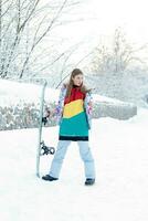 Young woman holding snowboard on her shoulders photo