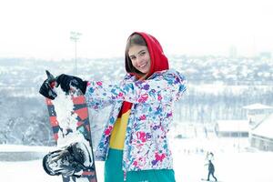 joven mujer participación tabla de snowboard en su espalda foto