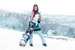 joven mujer participación tabla de snowboard en su espalda foto