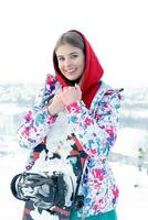 Young woman holding snowboard on her shoulders photo