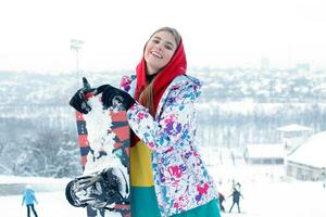 Young woman holding snowboard on her shoulders photo