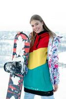 Young woman holding snowboard on her shoulders photo