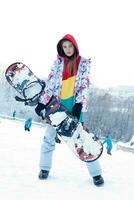 Young woman holding snowboard on her shoulders photo