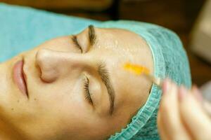 The cosmetologist puts a mask on the face of a young man. photo