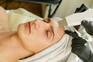 The cosmetologist makes the procedure ultrasonic face peeling photo